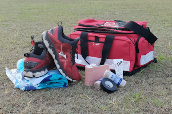 First Aid bag, medical and sports gear, used by a Sports Trainer. The gear is sitting on a grass oval